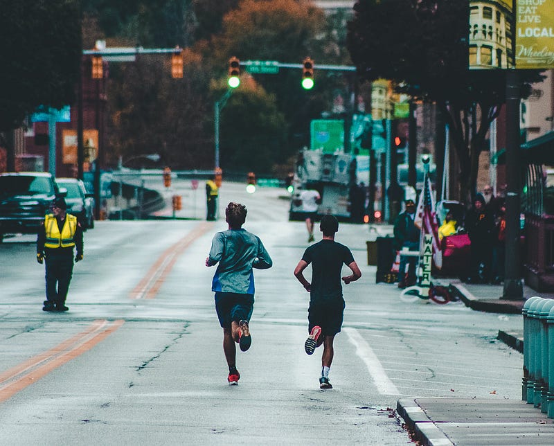 Two runners pushing their limits on a long road.