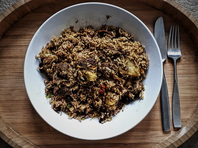 A delicious plate of curry goat with rice and peas